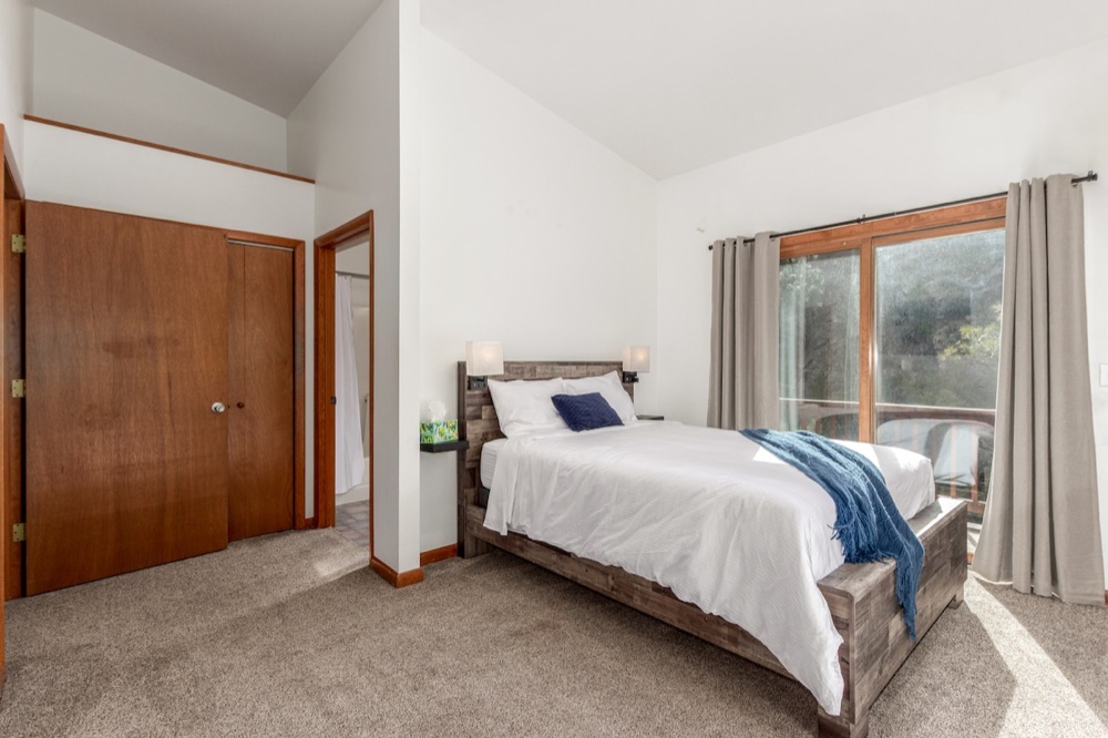 Bedroom with sliding doors to the deck and a view of the pines