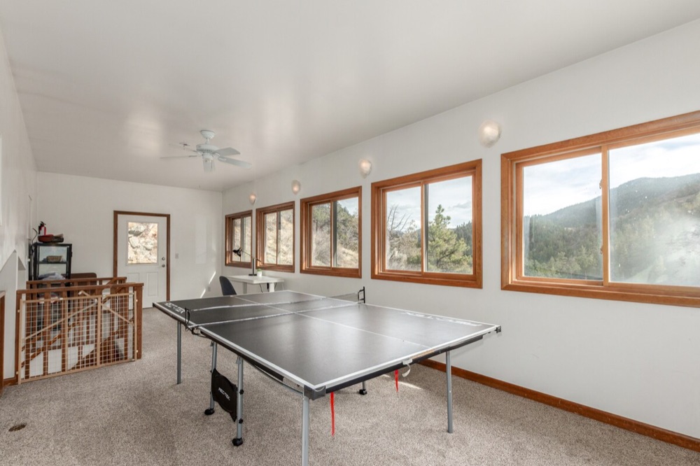 Game room with ping pong table and a row of windows looking out at the mountains